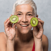 older woman with young looking skin holding avocados