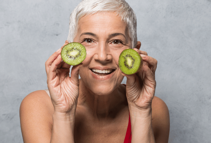 older woman with young looking skin holding avocados