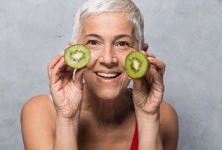 older woman with young looking skin holding avocados