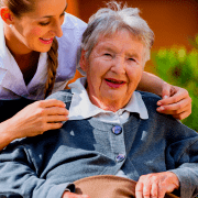 young female travel nurse RN wheels senior patient in assisted living facility