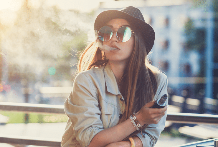 woman with sunglasses and hat on vaping hash